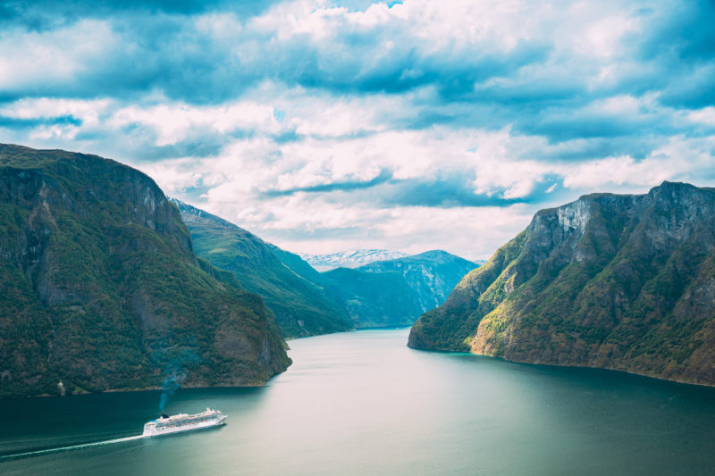 Positive Travel Iceland Guide Tourist Ship Ferry Boat Liner Floating In Amazing Fjord Sogn Og Fjordane. Summer Scenic View Of Famous Natural Attraction Landmark And Popular Destination In Summer.